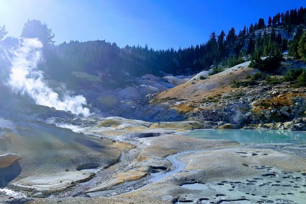 Landscape of Lassen Volcanic National Park in the middle of the day. Steam coming up from the ground.